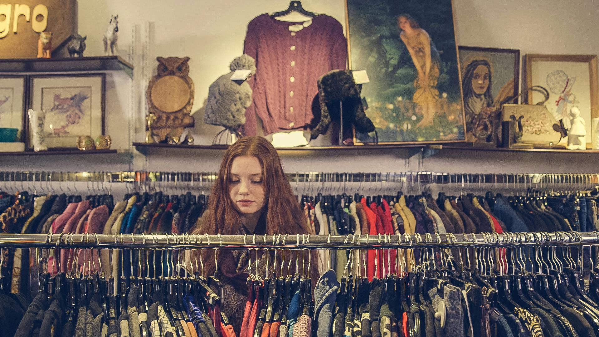 A woman explores racks of clothing in a cozy vintage shop